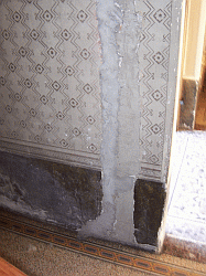 Graffito e finto marmo abrasi sulla parete delle scale